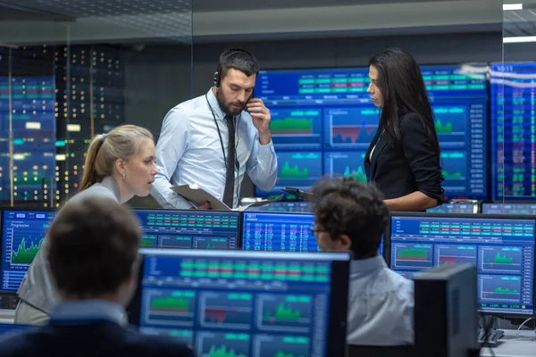 Multi-Ethnic Team of Traders is Busy Working at the Stock Exchange Office. Negociantes e corretores Comprar e vender ações no mercado. Monitores de exibição Infográficos, dados e números relevantes . — Fotografia de Stock