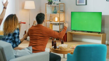 Oturma odasında bir koltukta oturan üç spor fanatiği Yeşil Krom Anahtar Ekran Maçı 'nı izliyor, Boynuzları kullanıyor, Takımları için tezahürat yapıyor ve Jest Yapan Kutlamalar' ı kazanıyor..