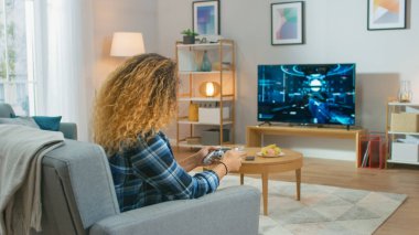 Oturma Odasında Oturan Kız Koltuk Tutucu Denetleyicisinde Bir Konsol Video Oyunu 'nda Oynayan, 3d TV' de Oynanan Eylem Atıcısı Oyunu.