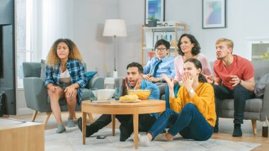 Ev Çeşitli Grup Arkadaşları 'nda birlikte televizyon izleyip, abur cubur yiyip, içki içiyorlar. Muhtemelen spor maçı ya da eğlence filmi izliyorlardır..