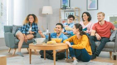 Ev Çeşitli Grup Arkadaşları 'nda birlikte televizyon izleyip, abur cubur yiyip, içki içiyorlar. Muhtemelen spor maçı ya da film izliyorlardır. Gençler Birlikte Eğleniyor.