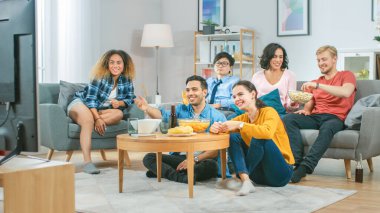Ev Çeşitli Grup Arkadaşları 'nda birlikte televizyon izleyip, abur cubur yiyip, içki içiyorlar. Muhtemelen spor maçı ya da film izliyorlardır. Gençler Birlikte Eğleniyor.