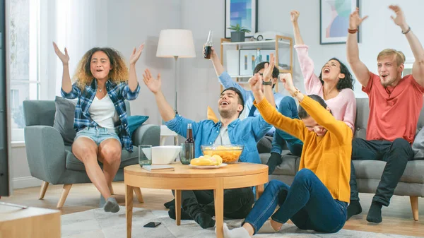 At Home Diverse Group of Sports Fans Sitting on Couch Watching Important Sports Game Match on TV, They Cheer for Team, Celebrate Victory after Team Scoring Winning Goal. Cozy Room with Snacks Drinks. — Stock Photo, Image