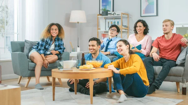 At Home Diverse Group Friends Watching TV Together, Eating Snacks and Drinking Beverage. They Probably Watching Sports Game or Movie. Young People Having Fun Together. — ストック写真