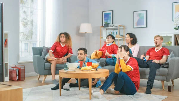 Στο Home Diverse Group of Sports Fans φορώντας ομοιόμορφο ρολόι αγώνα της ομάδας στην τηλεόραση, ζητωκραυγάζουν, αλλά η ομάδα χάνει. Άνετο δωμάτιο με σνακ και ποτά. — Φωτογραφία Αρχείου