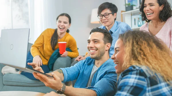 Eine Gruppe von Freunden nutzt Laptop im Wohnzimmer. glücklich schöne Mädchen und Jungs beim Live-Streaming. sie haben Spaß und lachen. — Stockfoto