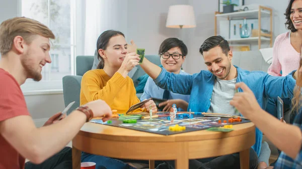 Diverse Group of Guys and Girls Playing in a Strategic Board Game with Cards and Dice. Reading Cards and Laughing. Friends Having Fun. Cozy Living Room in a Daytime — Stock Photo, Image