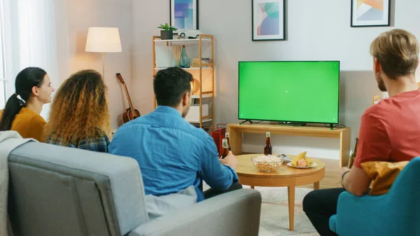 Amigos felices sentados en casa viendo la pantalla clave de croma verde, relajándose en un sofá. Ver partidos deportivos, Noticias, Sitcom TV Show o una película . —  Fotos de Stock