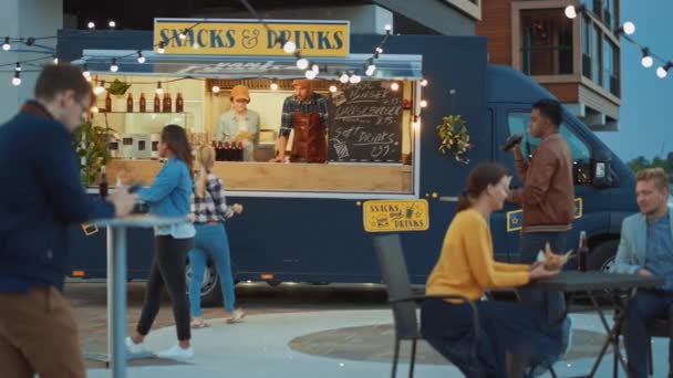 Food Truck Employee Hands Out Freshly Made Beef Burgers, Fritos e bebidas frias para jovens felizes Hipster Clientes. Caminhão comercial vendendo comida de rua em um bairro fresco moderno . — Vídeo de Stock