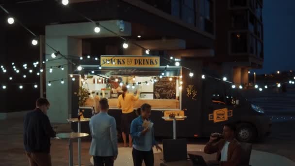 Food Truck Dipendenti mani fuori Freshly Made Beef Burgers, Fries e bevande fredde per Happy Young Hipster Clienti. Camion commerciale che vende Street Food in un quartiere fresco moderno. — Video Stock