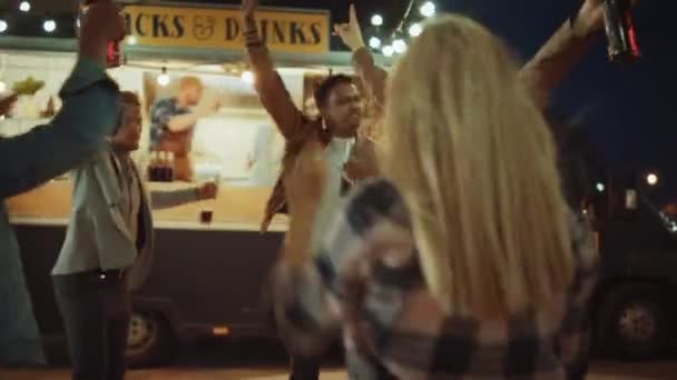 Grupo de amigos están teniendo una fiesta fuera de un Street Food Burger Café. Bailan y se mueven a la música de moda. Es de noche en un barrio moderno y fresco. Todos son felices y llenos de alegría . — Vídeo de stock