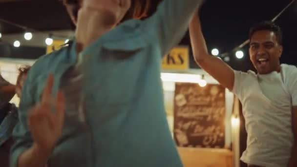 Groupe d'amis font une fête en dehors d'un café Burger Street Food. Portrait d'une jeune belle femme dansant sur la musique. C'est le soir dans un quartier moderne. Tout le monde est heureux et plein de joie — Video