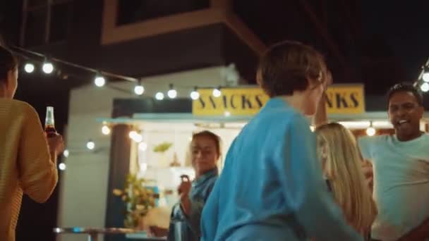 Grupp av vänner har fest utanför en Street Food Burger Cafe. De dansar och flyttar till Trendig musik. Det är kväll i ett modernt coolt grannskap. Alla är glada och fulla av glädje. — Stockvideo