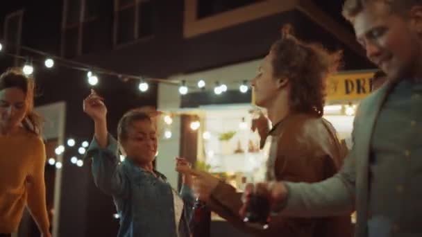 Vriendengroep geeft een feestje buiten een Street Food Burger Cafe. Ze dansen en bewegen naar trendy muziek. Het is avond in een moderne, coole buurt. Iedereen is gelukkig en vol vreugde.. — Stockvideo