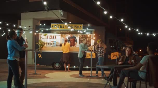 Foodtruck-Mitarbeiter verteilen Burger an glückliche junge Hipster-Kunden. Erfolgreiche Food-Truck-Mitarbeiter geben High Five. Lieferwagen verkauft Streetfood in modernem coolen Viertel. — Stockvideo