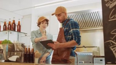 Başarılı Yemek Kamyoncusu ve Kahverengi Başlıklı Kadın Çalışanlar Tablet Bilgisayar kullanıyor. Kârlarını ve gelecekteki iş planlarını tartışıyorlar. Ticari Kamyon ya da Büfe Sokak Gıda ve İçecekleri Satıyor.