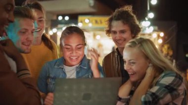 Güzel ve Yakışıklı Arkadaşlar, bir sokak yemekhanesinde bir masada dururken dizüstü bilgisayar kullanıyorlar. Video ya da Online Stream izliyorlar. Mutlular ve gülümsüyorlar..