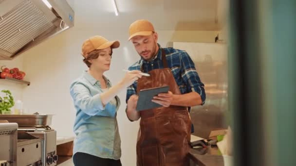 Los empleados exitosos de Food Truck Man and Woman en gorras marrones están usando una computadora de tableta. Discuten sus ganancias y planes de negocio futuros. Camión comercial o quiosco que vende comida y bebidas callejeras . — Vídeos de Stock