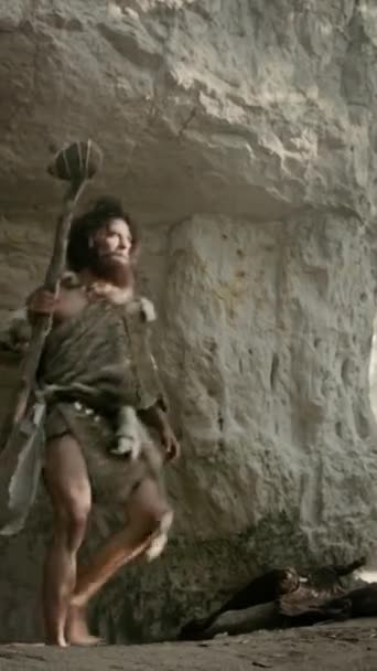 Urzeit-Höhlenmensch in Tierhaut und Pelzjagd mit einem steinernen Speer in der prähistorischen Höhle. Prähistorische Neandertaler-Jäger auf Schatzsuche. Videomaterial mit vertikaler Bildschirmausrichtung 9: 16