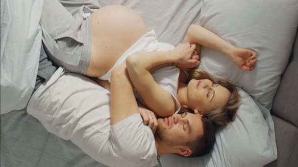 Šťastný mladý pár s těhotnou ženou spí spolu v posteli, sladké milující mladí lidé drží navzájem, zatímco spí. Video záběry s vertikální orientací obrazovky 9: 16 — Stock video