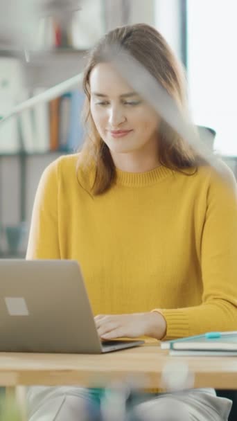 아름답고 똑똑 한 빨간 머리 여성 전문가가 책상 앞에 앉아서 컴퓨터로 일하고 있습니다. 밝고 현대적 인 오픈 스페이스 오피스. 수직 화면 방향 비디오 9: 16 — 비디오