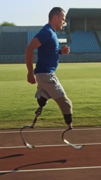 Ein athletisch behinderter, fitter Mann mit prothetischen Laufklingen trainiert im Stadion. Der beinamputierte Läufer joggt auf der Stadionbahn. Motivations-Paralympics-Sieger. Video zur vertikalen Bildschirmorientierung 9: 16 — Stockvideo