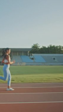 Açık Mavi Atletizm Üstündeki Güzel Fitness Kadını ve Leggings Açık Hava Stadyumu 'nda Koşuya Başlıyor. Sporla uğraşan bir sporcu. Ağır çekim. Dikey Ekran Yönlendirme Videosu 9: 16