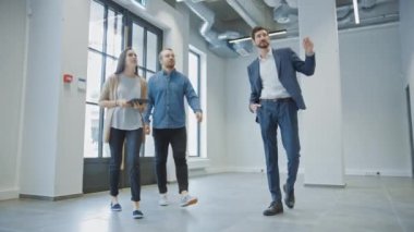 Genç Erkek ve Bayan Hippilere Yeni Boş Ofis Alanını Gösteren Emlakçı. Girişimciler Komisyoncuyla bir tabletle buluştu ve satın almak veya kiralamak istedikleri tesisi tartıştılar.