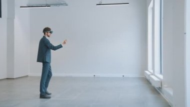 Sanal Gerçeklik Gözlüklerindeki İşadamı Boş Ofiste Duruyor ve Haritasını Yapıyor. Girişimci Uzayda Sanal Parçaları Hareket ettiriyor. Video Yazılım için İzleme Noktaları Var.