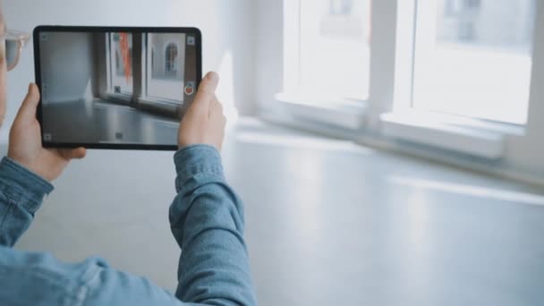 Joven Hipster Hombre con gafas de pie en la oficina vacía y mapearlo con un software de realidad aumentada en una Tablet Computer. Pantalla con la aplicación de la cámara tiene puntos de seguimiento para el software de vídeo . — Vídeo de stock