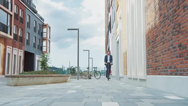 Jeune homme d'affaires en costume pour travailler sur un scooter électrique. Un entrepreneur moderne utilise le transport écologique contemporain pour se rendre à une réunion de bureau. Vidéo au ralenti . — Video