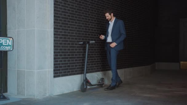 Un homme d'affaires en costume active un scooter électrique avec un smartphone. Il analyse le QR Code. Entrepreneur utilise le transport écologique contemporain pour se rendre à une réunion de bureau. Vidéo au ralenti . — Video