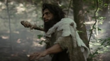 Hayvan Derisi Tutucu Taştan Mızraklı İlkel Mağara Adamı Etrafa Bakınıyor, Hayvan Avı Avında Tarih Öncesi Ormanı keşfediyor. Neanderthal Ormanda Avlanmaya Gidiyor