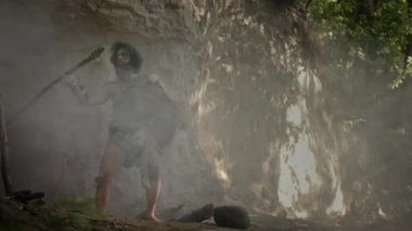 Hayvan derisi ve kürkü olan ilkel mağara adamı mağarasından çıkıp tarih öncesi ormanı avlamaya hazır hale geldi. Neanderthal Ormana Avlanmaya Gidiyor