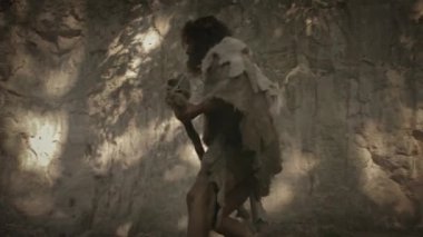 Hayvan Derisi Tutacağı Taşı Giyen İlkel Mağara Adamı Mağaradan çıktı ve etrafına baktı, Tarih Öncesi Ormanı keşfetti, Hayvan Avına Hazır. Neanderthal Ormana Avlanmaya Gidiyor