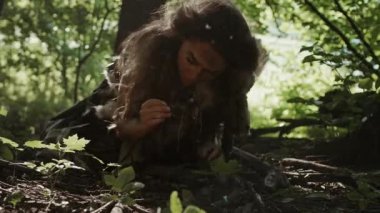 Tarih öncesi mağara kadını avcı-toplayıcı ormanda fındık ve dut arıyor. İlkel Neandertal Kadın Güneşli Ormanda Yiyecek Buluyor