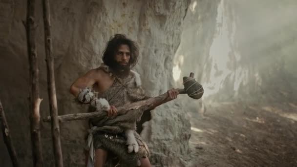Urzeit-Höhlenmensch mit Tierhaut hält steinernen Hammer in der Hand, kommt aus der Höhle und schaut sich im Urwald um, bereit, tierische Beute zu jagen. Neandertaler auf der Jagd in den Dschungel Bogenschuss