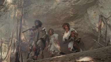 Avcı-Toplayıcılar kabilesi Hayvan Derisi Tutma Taşı Taşı Giyen, Mağara girişinin yanında duran Ormanda Avlanmaya Hazır Neandertal Ailesi veya Göç