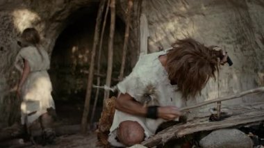 Primeval Caveman Bow Matkap Yöntemi ile Yangın yapmaya çalışıyor Hayvan Deri Giyen. İnsan Uygarlığı Tarihinde Neandertal Kindle İlk İnsan Yapımı Ateş. Yemek Pişirmek için Ateş Yapmak. Çekimi Yakınlaştır