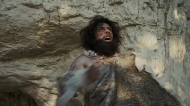 Portrét pravěkého jeskynního muže v kůži zvířete dělá agresivní hrudník bití a křičí, brání svou jeskyni a území v pravěkém lese. Prehistorický neandrtálec nebo vůdce Homo Sapiens