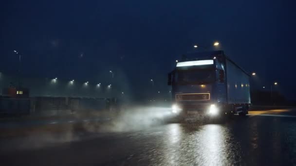 Blue Long Haul teherautó teherautóval, teherautóval, tele áruval, éjjel utazik az autópályán, átszeli a kontinenst esőn, ködön, havon keresztül. Ipari raktárak területe. Első lövés után. — Stock videók