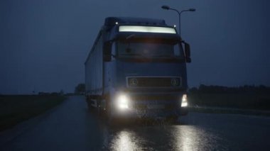 Kargo Kargo Karavanı 'yla Long Haul Semi-Truck Kargo Yolunda Gece Yolculuğu Kıtayı Yağmur, Sis ve Karla Geçiş. Endüstriyel Depo Bölgesi. Yavaş Çekim Sonrası Önde
