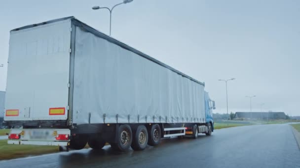 Semirremolque de larga distancia con remolque de carga lleno de mercancías viaja por la carretera. Conducción diurna a través del continente a través de la lluvia, la niebla. Área de Almacenes Industriales. Vista posterior siguiente disparo — Vídeo de stock