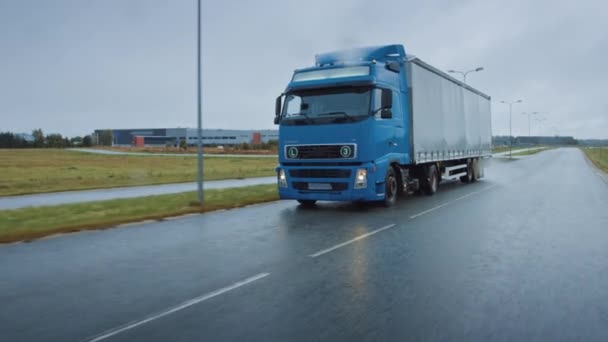 Long Haul semi-caminhão com reboque de carga cheio de mercadorias viaja na estrada da estrada. Diurno dirigindo através do continente através da chuva. Área de Armazéns Industriais. Vista frontal seguinte tiro — Vídeo de Stock