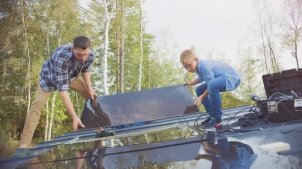 Vater und Sohn installieren Sonnenkollektoren auf Metallbasis. Sie halten die Tafeln an einem sonnigen Tag auf einem Hausdach. Konzept der ökologischen erneuerbaren Energien zu Hause und Qualität der Familienzeit. — Stockvideo