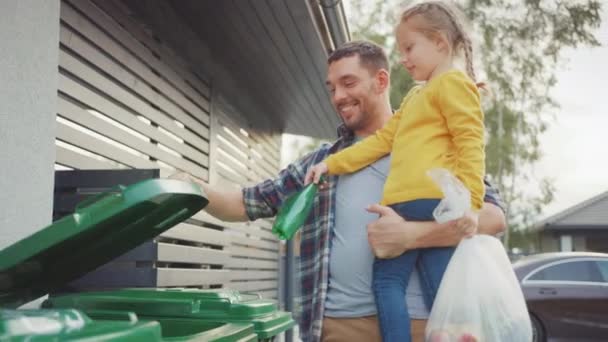 Padre feliz sosteniendo a una joven y yendo a tirar una botella vacía y desperdicio de comida a la basura. Utilizan contenedores de basura correctos porque esta familia está clasificando los residuos y ayudando al medio ambiente . — Vídeos de Stock