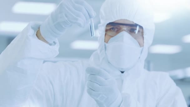 在实验室研究人员 科学家中穿着防护服 带实验药品试管 并对试管进行检查 — 图库视频影像