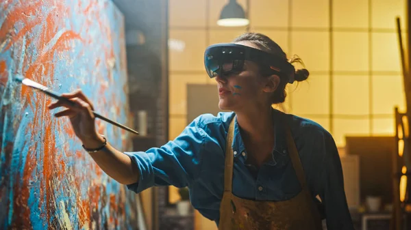 Talentosa artista femenina que usa auriculares de realidad aumentada que trabajan en la pintura abstracta, utiliza el pincel de pintura para crear un nuevo concepto de arte utilizando la interfaz de realidad virtual. Estudio moderno creativo de alta tecnología — Foto de Stock