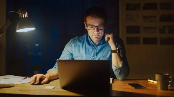 Homme professionnel assis à son bureau dans Office Studio Travailler sur un ordinateur portable le soir. Homme analysant les statistiques . — Photo