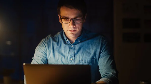 Homme professionnel assis à son bureau dans Office Studio Travailler sur un ordinateur portable le soir. Homme travaillant avec des données, analysant des statistiques, écrivant l'information . — Photo